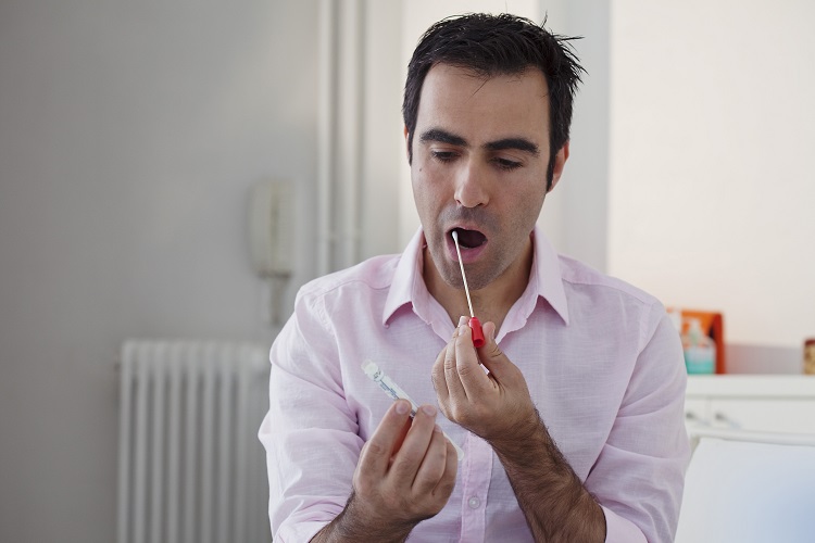 man swiping his saliva to undergo a preventative genetics screening